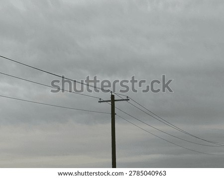 Utility power infrastructure beneath dramatic overcast sky showing electrical transmission lines and moody outdoor energy network scene