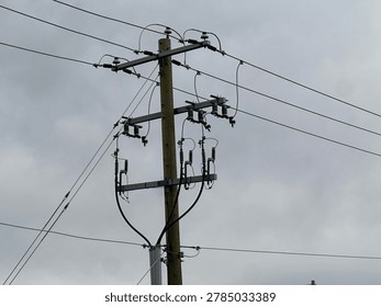 Utility power pole and electrical lines against overcast sky showing infrastructure and energy transmission outdoors