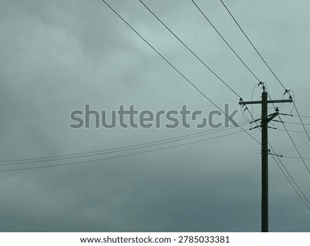 Utility power pole and electrical lines against overcast sky showing infrastructure and energy transmission outdoors