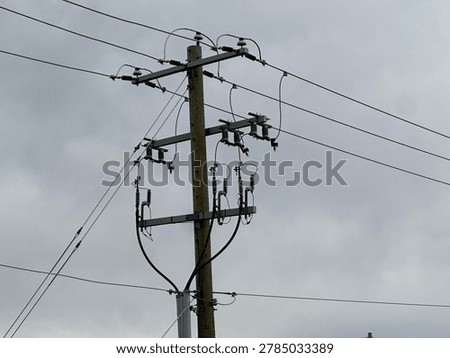 Utility power pole and electrical lines against overcast sky showing infrastructure and energy transmission outdoors