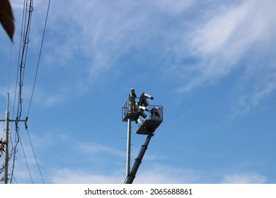 Utility Repairmen On Elevated Platform, Fixing Floodlights Over Sports Field