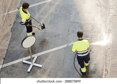 Utility Service Company Man  Worker Cleaning The Street  With Water Pressure At City