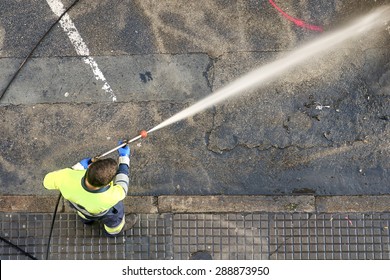 Utility Service Company Worker Cleaning The Street City  With Water Pressure 