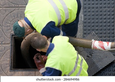 utility service company workers moves the manhole cover to cleaning the sewer line for clogs aerial view
