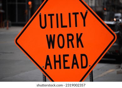 Utility Work Ahead orange construction street sign in urban city