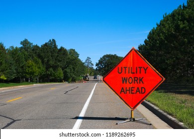 Utility Work Ahead Sign With Service Vehicle Down The Street