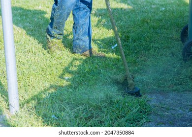 A Utility Worker In A Green Lawn With Lawn A Brushcutter Cutting Grass