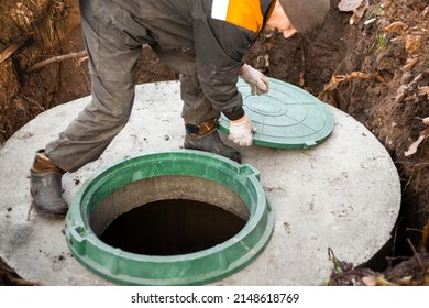 A Utility Worker Opened A Well Hatch For Sewerage Maintenance And Pumping Out Feces. Septic On A Residential Lot.