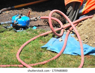 Utility Worker Repairing An Underground Broken Water Pipe Outside.