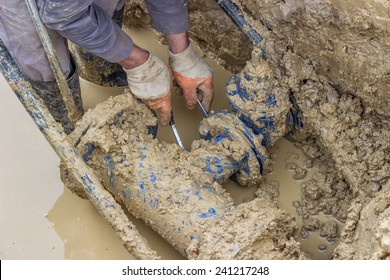 Utility Worker Using Tool To Repair The Broken Pipe Valve For Commercial Building Water Supplies. Utility Worker Fixing Broken Water Main.