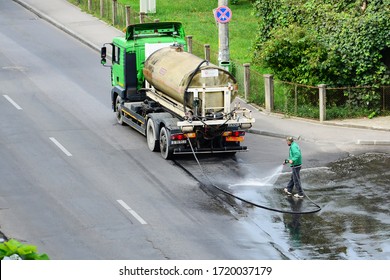 Utility worker washes and disinfects the asphalt on the street with a hose connected to a cistern truck in cluj-Napoca, Romania on August 26, 2014