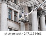 Utility workers on lift platform, facade restoration on historic building with ornate columns, preservation of urban architecture. Men on lift platform clean and maintain exterior of historic building