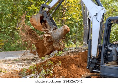 Utilizing skid steer tractor to remove roots and clear land for housing complex construction
