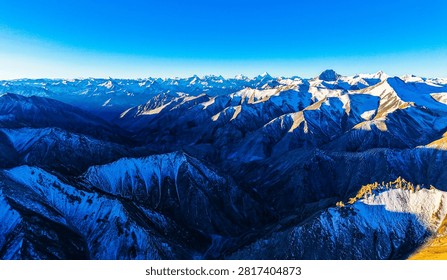 Utilizing a unique aerial perspective, this photograph captures the awe-inspiring sunrise deep within the Karakoram Range in Yecheng County, Xinjiang. The frame showcases several legendary 8,000-meter peaks, featuring Mount K2 and Broad Peak. The morning sun bathes the razor-sharp ridges in brilliant golden light, creating a dramatic alpenglow effect. This visual masterwork highlights the supreme majesty of Earth's most extreme high-altitude wilderness and the unmatched depth of drone landscape photography.