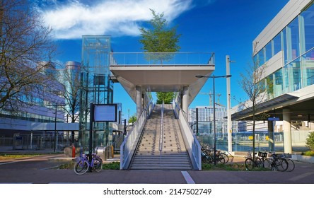 Utrecht (Moreelsebrug), Netherlands - April 4. 2022: View Over Square On Futuristic Modern Architecture Design Stairway To Railway Bridge, Green Trees, Blue Sky