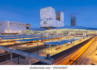 Utrecht, Netherlands cityscape over train station platforms at dawn.