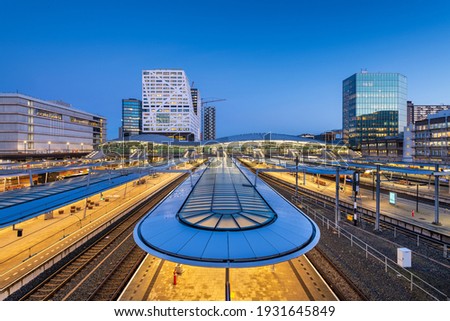 Utrecht, Netherlands cityscape over train station platforms at dawn.