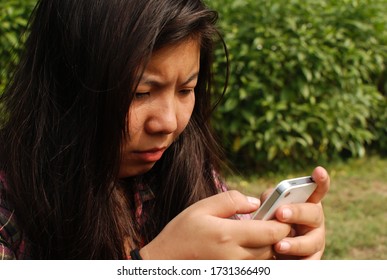 Uttar Pradesh/India - May 14, 2020: Girl Using Her White Mobile Phone In The Park, And Watching A Video On On You Tube 