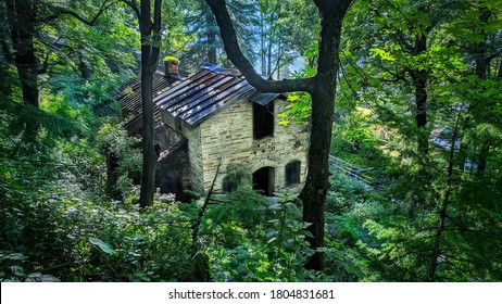 uttarakhand,india:old house in forest.this is a picture of a broken and abandoned house in forest surrounded with trees and greenery.stone house in forest.