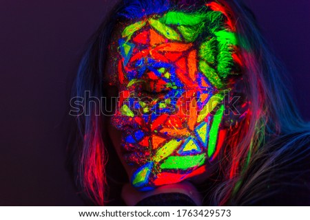 UV Fluorescent paint reflect under the blacklight on a beautiful young lady's face