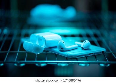 UV light sterilization of smartphone and earbuds. COVID-19 prevention concept.