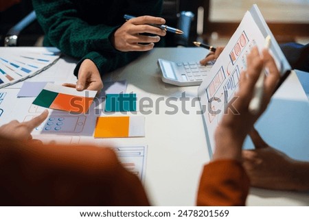 UX developer and ui designer brainstorming about mobile app interface wireframe design with customer breif and color code at office.