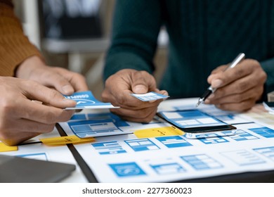 ux developers and ui designers, data researchers brainstorm on  tabletop mobile app interface wireframe design with client summary color codes the modern office Creative Digital Development Agency.