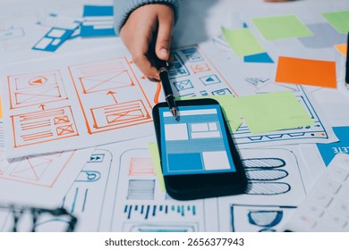 UX UI designer testing prototype on a phone, discussing and brainstorming on wireframes for a website and mobile app prototype, in the concept of website and mobile application design concept.