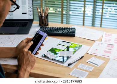 UX UI designer testing prototype on a phone, working on wireframes for a website and mobile app prototype, in concept of website and mobile application design concept.