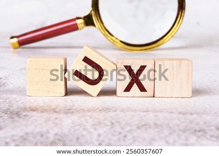 UX User Experience development and design concept. The abbreviation UX written on wooden cubes with a magnifying glass in the background.