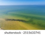 Uzava, Latvia - August 06, 2024. Shallow water of Baltic sea with sand and water grass structure by lighthouse