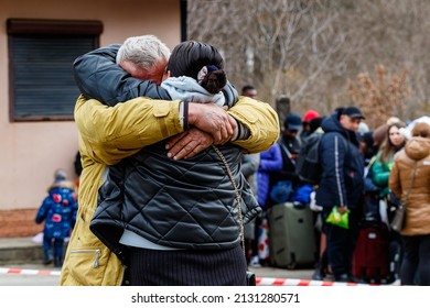 Uzhhorod, Ukraine - February 26, 2022: A man on the background of Ukrainian refugees says goodbye to his wife who is fleeing Russian aggression. Refugees on the Ukrainian-Slovak border.