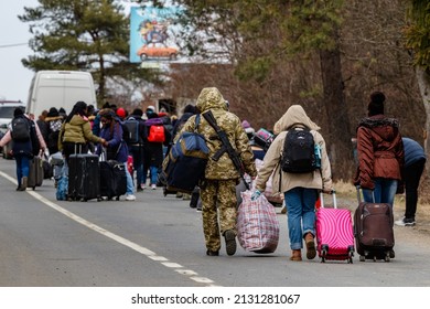 Uzhhorod, Ukraine - February 26, 2022: Ukrainian border guard helps to carry bags to refugees leaving the country through the Ukrainian-Slovak border.