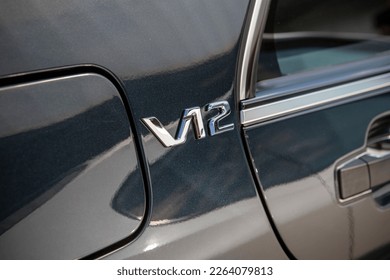 ''V12'' badge indicating the presence of an engine assembled from twelve cylinders. A large v-shaped engine, common in large representative limousines or sports vehicles. A sign of luxury.