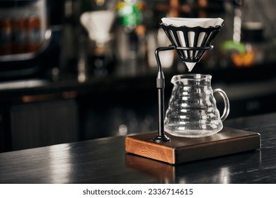 V-60 style method, dripper stand with filter bag above glass coffee pot on black wooden counter - Shutterstock ID 2336714615