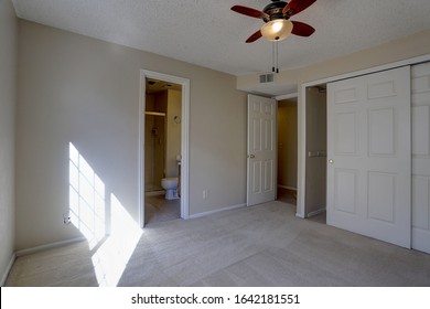 Vacant, Carpeted Bedroom With Ceiling Fan In Condominium Apartment Complex