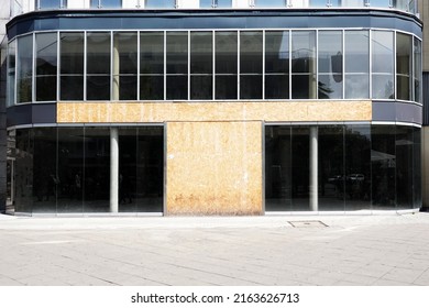 vacant commercial real estate with modern glass storefront boarded up after business closure
