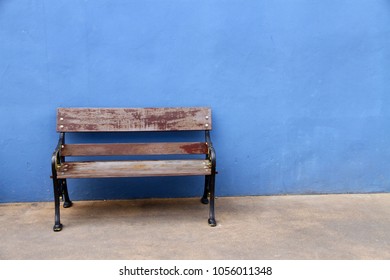 The Vacant Park Bench In Front Of The Background Of The Pale Blue Wall. The Concept Of Lonely, Independent, Liu Xiaobo, Empty Chair, Alone.