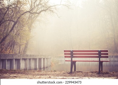 A vacant riverside bench on a foggy morning