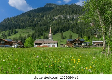 Vacation in Allgäu, Bavaria: The beautiful remote Hintersteiner valley with church and houses in the middle of the mountains