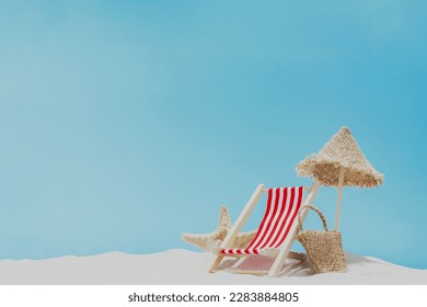 Vacation, beach, travel, relaxation concept. Symbolic background with beach sand, shell, mini sun lounger, beach chair, wooden lounge, beach bag, blue sky, sea or ocean. Minimalism with copy space