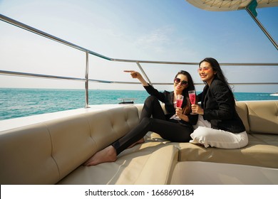 Vacation, drinking, couple and friendship concept. Asian business women relaxing on the yacht with glasses of wine.