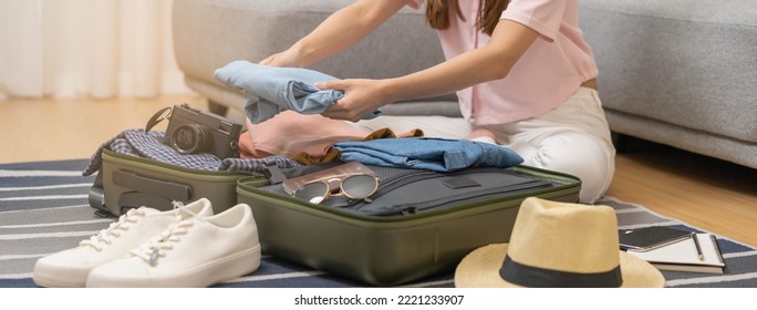 Vacation, holiday travel, traveler asian young woman, girl hand folding clothes packing and preparing stuff into luggage or baggage bag case for journey trip, preparation for journey voyage at home. - Powered by Shutterstock