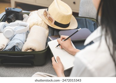 Vacation, holiday travel, traveler asian young woman, girl hand check list note after packing, preparing stuff into luggage or baggage bag case for journey trip, preparation for journey voyage at home - Powered by Shutterstock