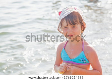 Vacation and holidays concept. Humorous portrait of young child girl relaxing on beach enjoying sun and sea on sunny summer day.