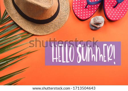 Vacation on the beach. Flat lay on orange coral background. Fern, hat, flip flops. Hello summer text