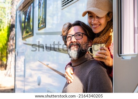 Vacation on camper van for adult people enjoying nature and free parking. Man and woman couple in travel holiday on motor home off grid lifestyle. Female hug male with love and intimacy. Green