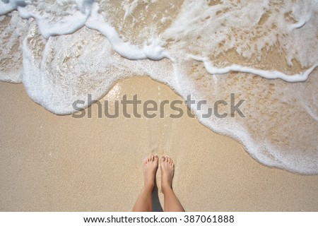 Vacation on ocean beach, feet on sea sand
