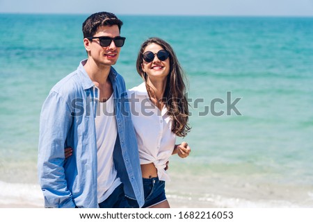 Vacation romantic lovers young happy couple holding hands walking on sand by sea having fun and relaxing together on tropical beach.Summer vacations and travel