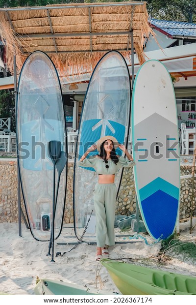 vacation, surfing, water sport and people concept -\
young woman in swimsuit with surfboard, windsurf or paddle board on\
summer beach